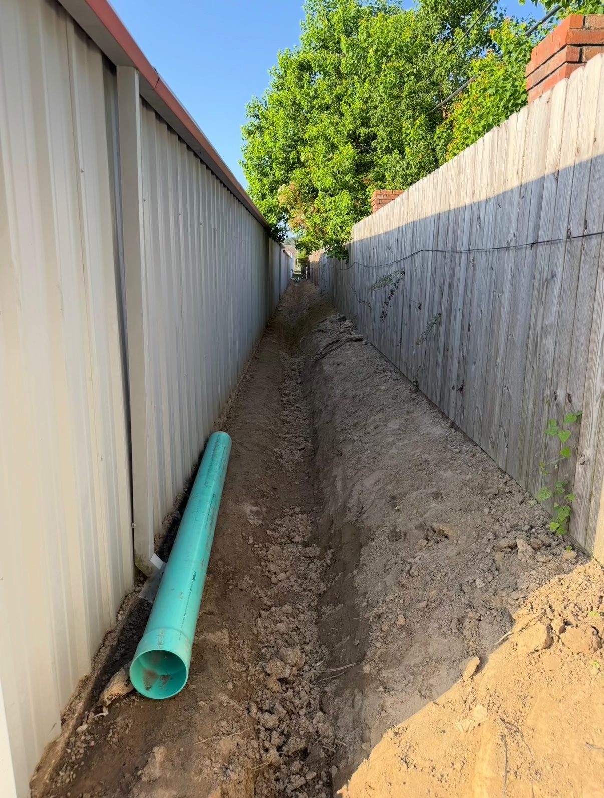 Drainage trench excavated with the new drain line staged alongside